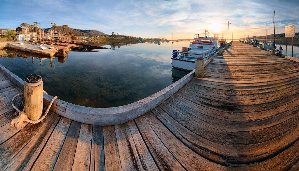 Wooden dock with boats docked, surrounded by calm waters.